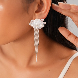 Close-up of sparkling crystal flower tassel earrings worn on ear for stylish look