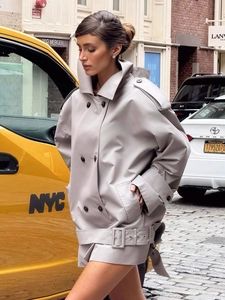 Detail of light grey double-breasted trench jacket with wide collar and waist belt