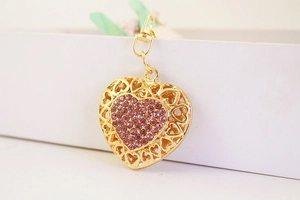 Close-up of golden hollow heart keychain featuring sparkling inlaid pink rhinestones