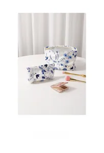 Gros plan d'un ensemble de deux sacs en coton blanc avec broderie florale bleue et logo