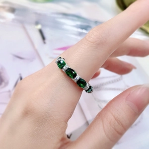 Close-up of elegant 925 silver ring with five oval green emeralds on a model's hand