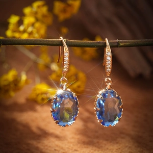 Detail view of gold oval blue gemstone earrings with zircon inlay on a branch
