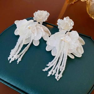 Elegant white floral tassel earrings with multilayer petals on a green jewelry box