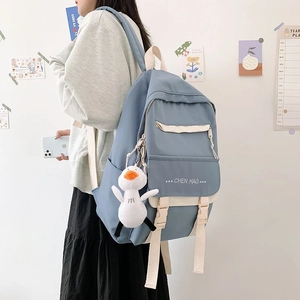 Side view of a light blue and beige school backpack featuring a cute duck pendant accessory