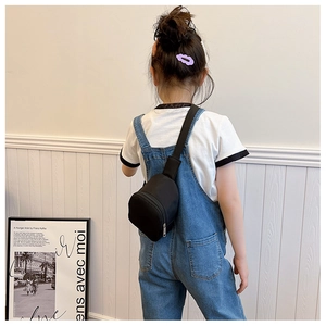 Rear view of a child wearing a black minimalist chest bag with adjustable strap