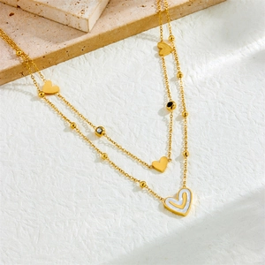 Double-layered gold-plated stainless steel necklace with heart pendants on stone texture