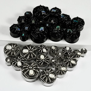 Detail showing various sizes of spider-shaped stainless steel ear gauges with shell inlay