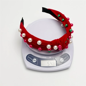Serre-tête en velours rouge avec nœud, perles et strass sur une balance pesant 54,8 g