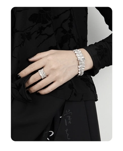 Detailed view of silver rings and bracelets featuring irregular pleated metal texture