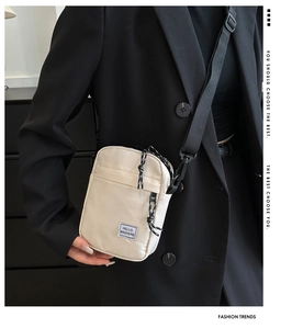 Detail of beige nylon crossbody bag showing zip pockets and Hello Weekend label texture