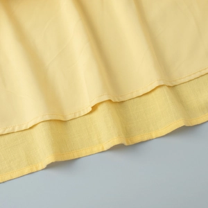 Detail of light yellow double-layer hem with fine stitching and textured fabric finish