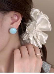 Gros plan d'une boucle d'oreille ronde bleu clair portée par un mannequin pour le printemps
