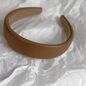 Detail view of brown faux leather headband with lychee texture and non-slip lining