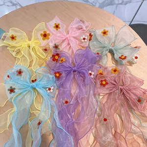 Colorful floral mesh bow hair clips for girls in various pastel colors on wooden background