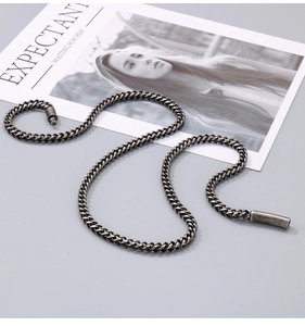 Detailed view of vintage silver steel keel chain necklace with cylindrical ends on magazine