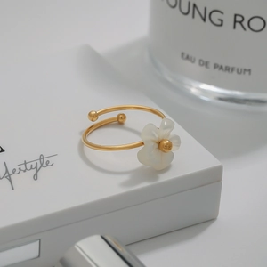 Macro shot of 18K gold plated floral open ring with white petal detail on jewelry box