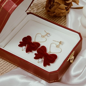 Detail of vintage red velvet bow earrings with gold heart frame and white pearl in a box