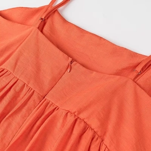 Détail du tissu texturé orange avec fines bretelles et fermeture éclair invisible
