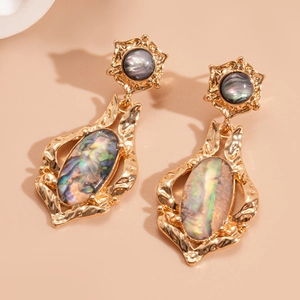 Close-up of vintage gold hammered earrings with oval abalone shell pendants