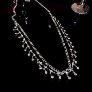Detail of silver double-layer body chain featuring sparkling rhinestone charms on dark background
