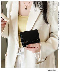 Close-up of black patent leather mini wallet with V-shaped flap and glossy finish