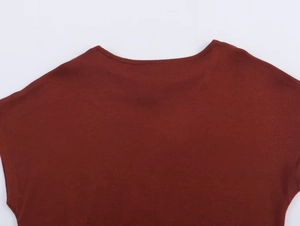 Détail de l'encolure et de l'épaule d'un haut en maille rouge foncé sur fond blanc