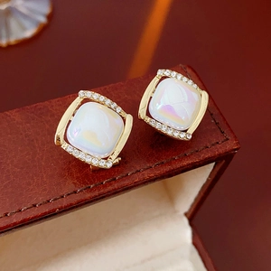 Détail macro de boucles d'oreilles carrées avec pierre opale et bordure en cristal doré