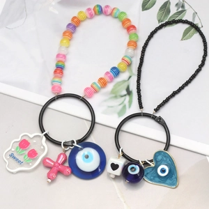 Colorful Evil Eye keychain with resin beads and sweet heart charms on a grey surface