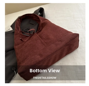 Detail of burgundy faux suede tote bag with drawstring closure on textured fabric