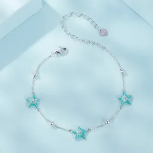 S925 sterling silver starfish bracelet with light green enamel pendants on blue surface