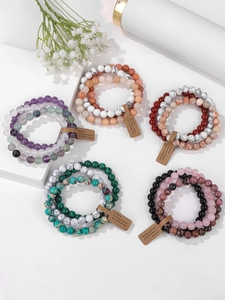 Detail view of five natural gemstone bead bracelets with brown tags on white background