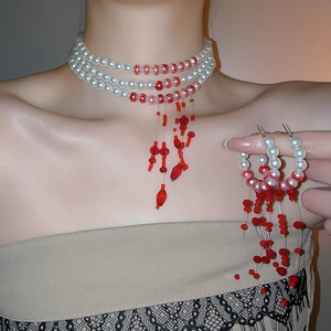 Detailed shot of multi-layer pearl necklace and earrings with red beaded fringe tassels
