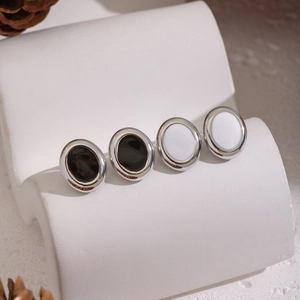 Classic geometric oval stainless steel earrings in black and white enamel on a display stand