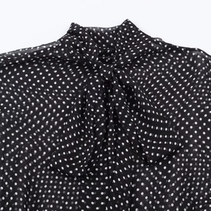 Dettaglio del tessuto nero a pois con elegante scollatura a fiocco annodato