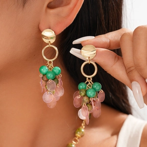Detail of bohemian gold earrings with green beads and translucent pink shell pendants