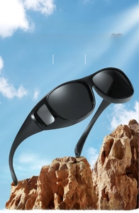 Detail of polarized sports sunglasses with side windows on a rock against a blue sky
