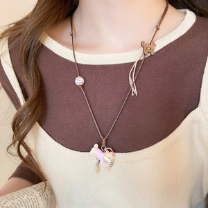 Close-up of cute cartoon cat pendant with pink striped outfit on brown cord necklace