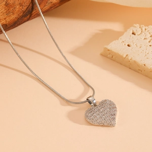 Close-up of a silver heart pendant with sparkling crystals on a sleek snake chain