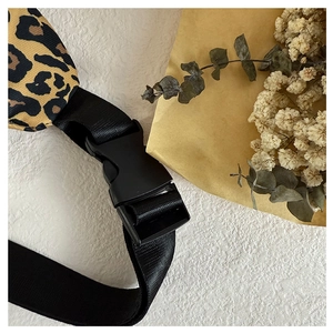 Detail of the leopard print fanny pack featuring a black buckle and nylon strap