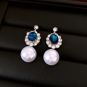 Detail of silver pearl earrings with blue oval stones in a luxury black display box