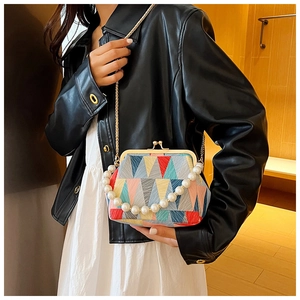 Detail of colorful geometric patchwork handbag with pearl handle and metal chain