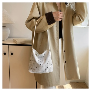 Close-up of a white polka dot shoulder bag worn with a khaki trench coat for a stylish look