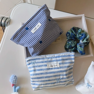 Detail view of blue striped and plaid cotton pouches with delicate floral embroidery