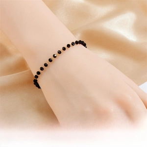 Detail of bohemian gold chain bracelet with black resin beads worn on a wrist