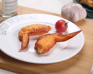 Macro detail of realistic roasted chicken wing models on a white plate in a cozy kitchen set