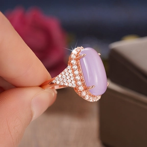 Macro shot of rose gold ring featuring a large oval purple gemstone and cubic zirconia