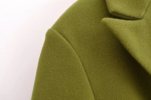 Dettaglio macro del cappotto di lana verde con focus su spalla e texture del collo