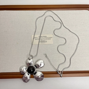 Detail of vintage silver flower pendant with black gemstone on sleek snake chain