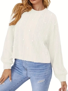 Détail d'un pull blanc en maille côtelée orné de perles élégantes et texturées