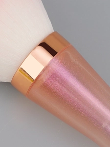 Macro shot of soft gradient bristles and rose gold ferrule on a glittery makeup brush